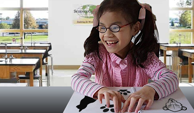 Student exploring tactile reading material at a desk.