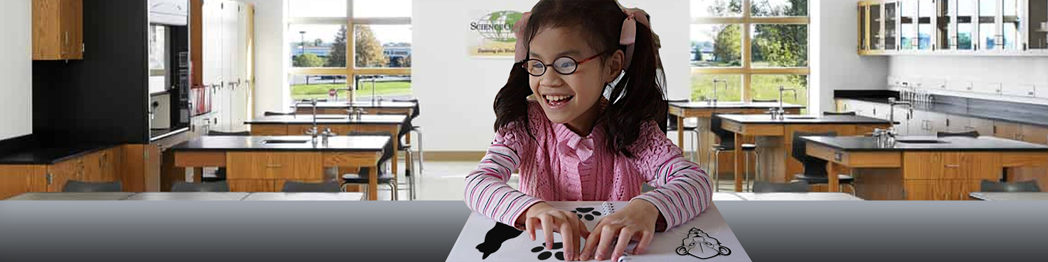 Student exploring tactile reading material at a desk.